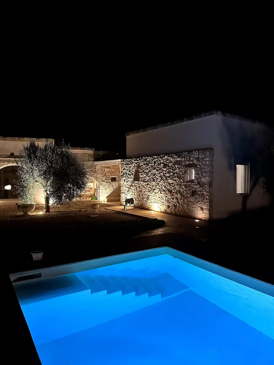 The pool lit at night, with steps into the water