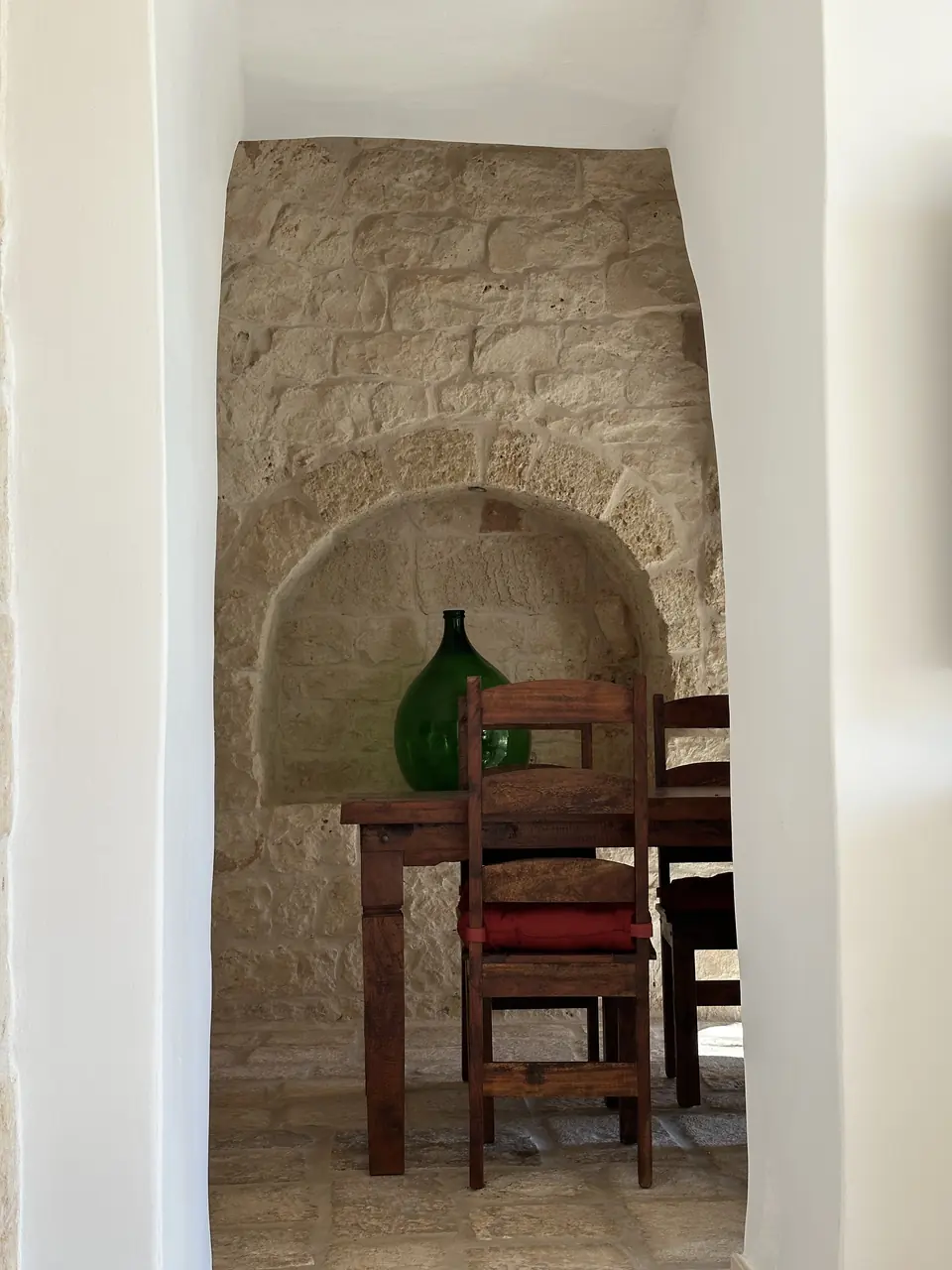 Stone niche with a chair and a glass demijohn