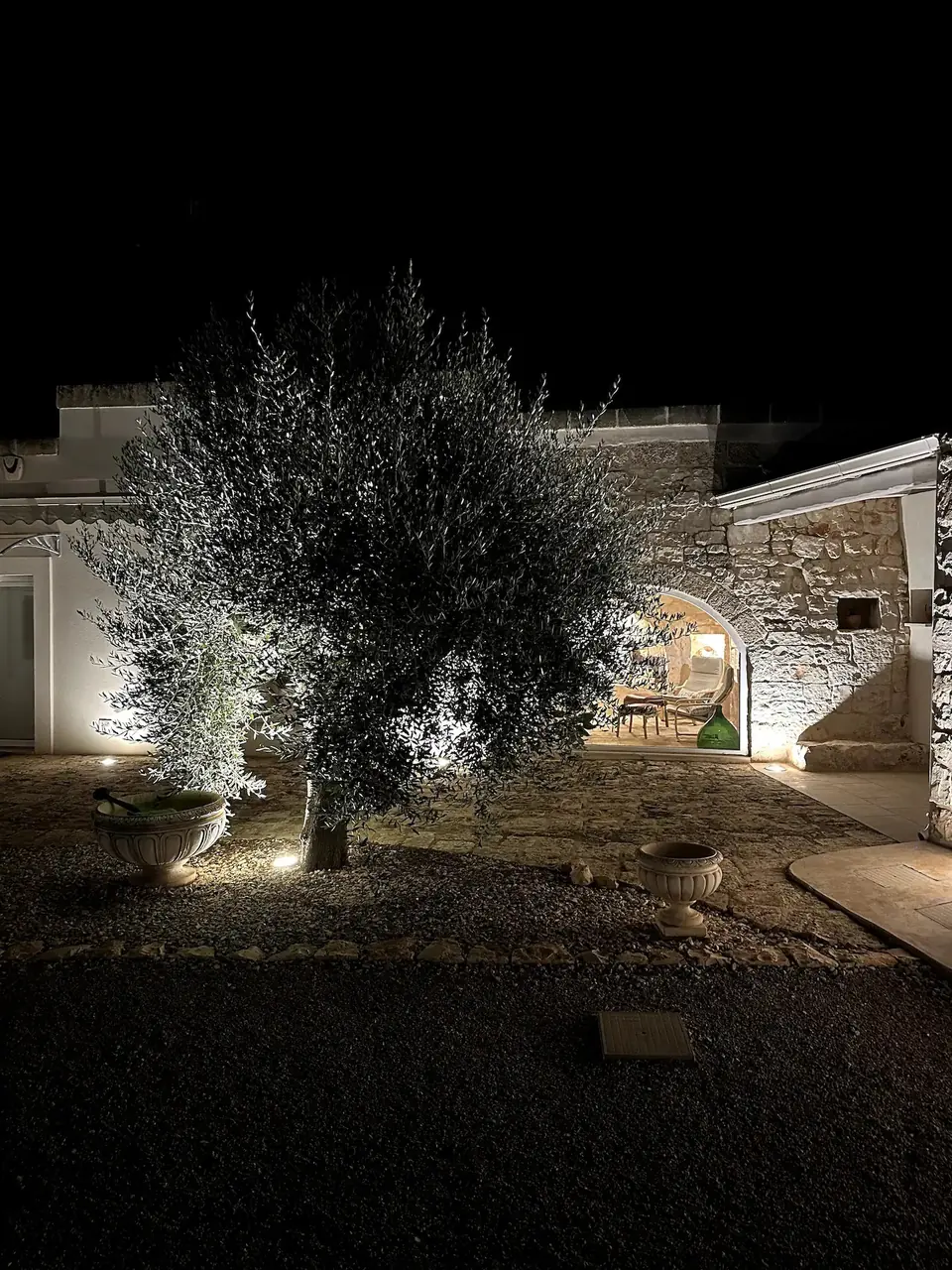 Villa El Carmen lit up at night, with an olive tree in front